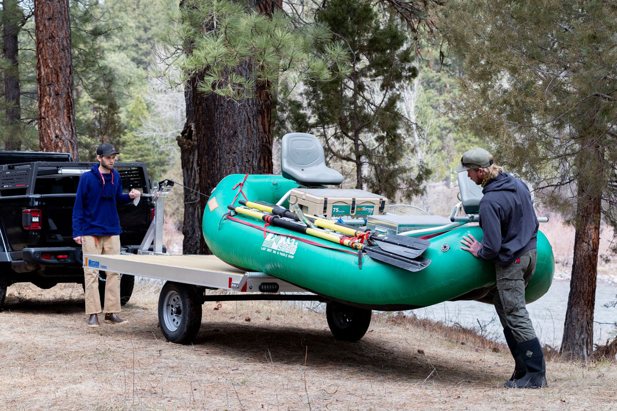 Two anglers unloading a fishing raft from an ALCOM trailer in Montana