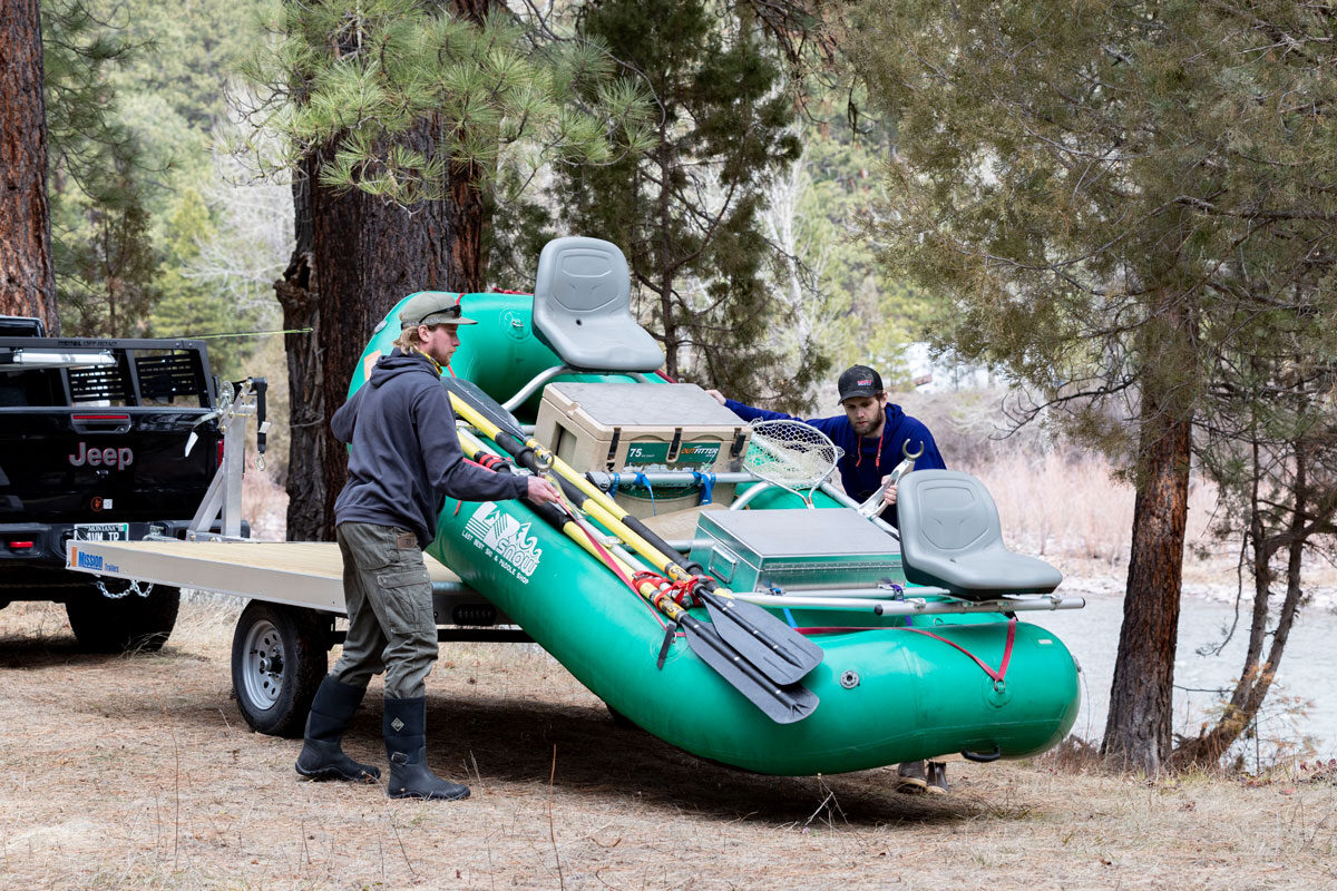 Two anglers unloading an inflatable fishing raft from an ALCOM trailer