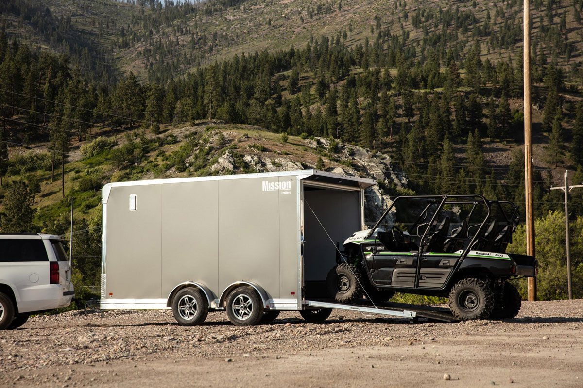 UTV backing out of a parked enclosed aluminum ALCOM side by side trailer in Montana