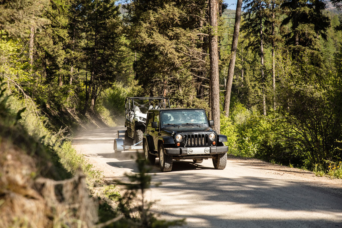 Jeep towing an aluminum ATV trailer from ALCOM on a mountain road in Montana