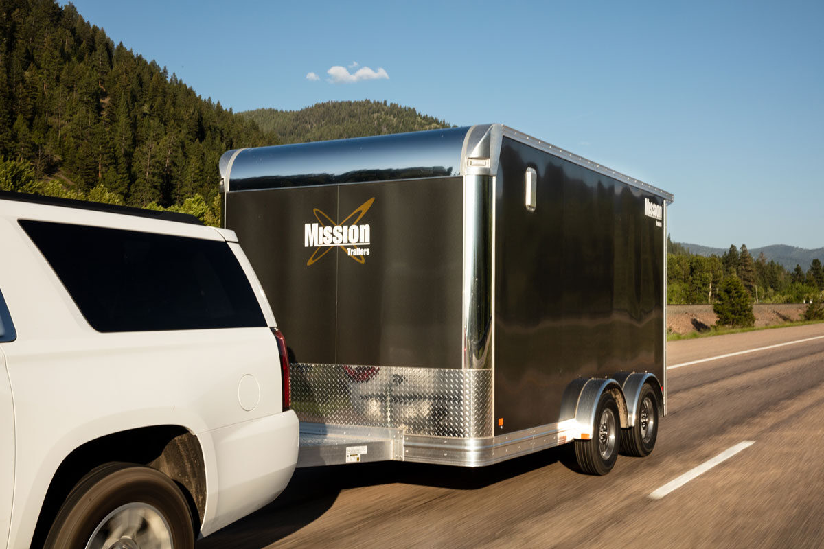 White SUV towing Pinnacle Series enclosed UTV hauler on the highway