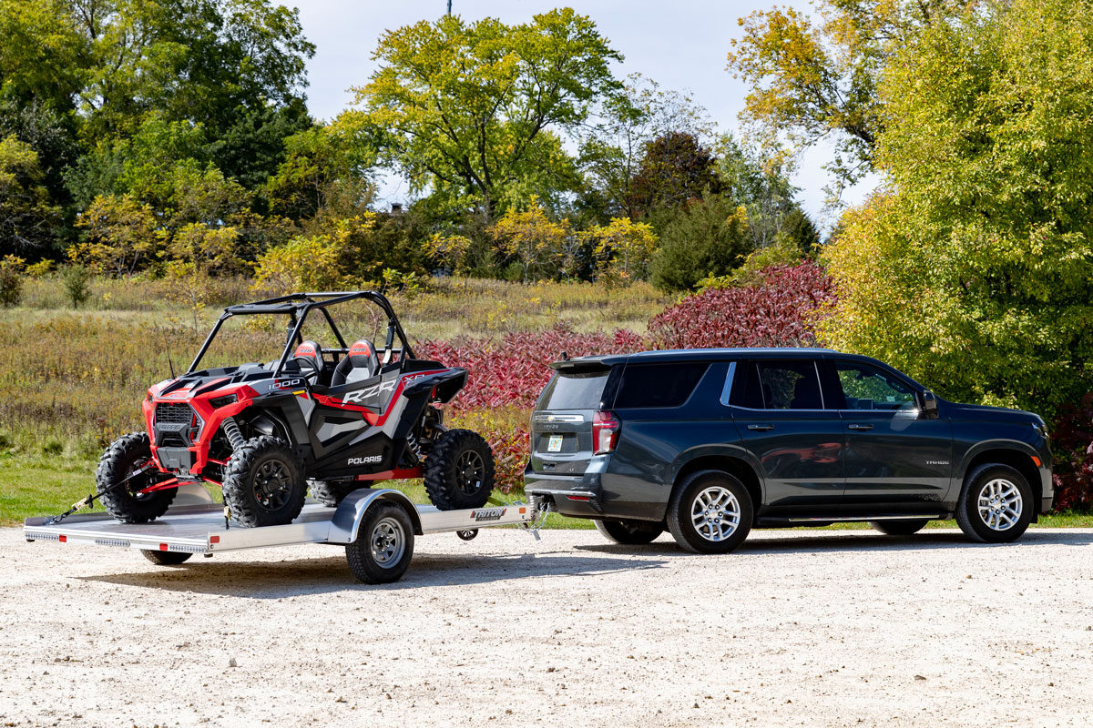 SUV with open UTV trailer parked 