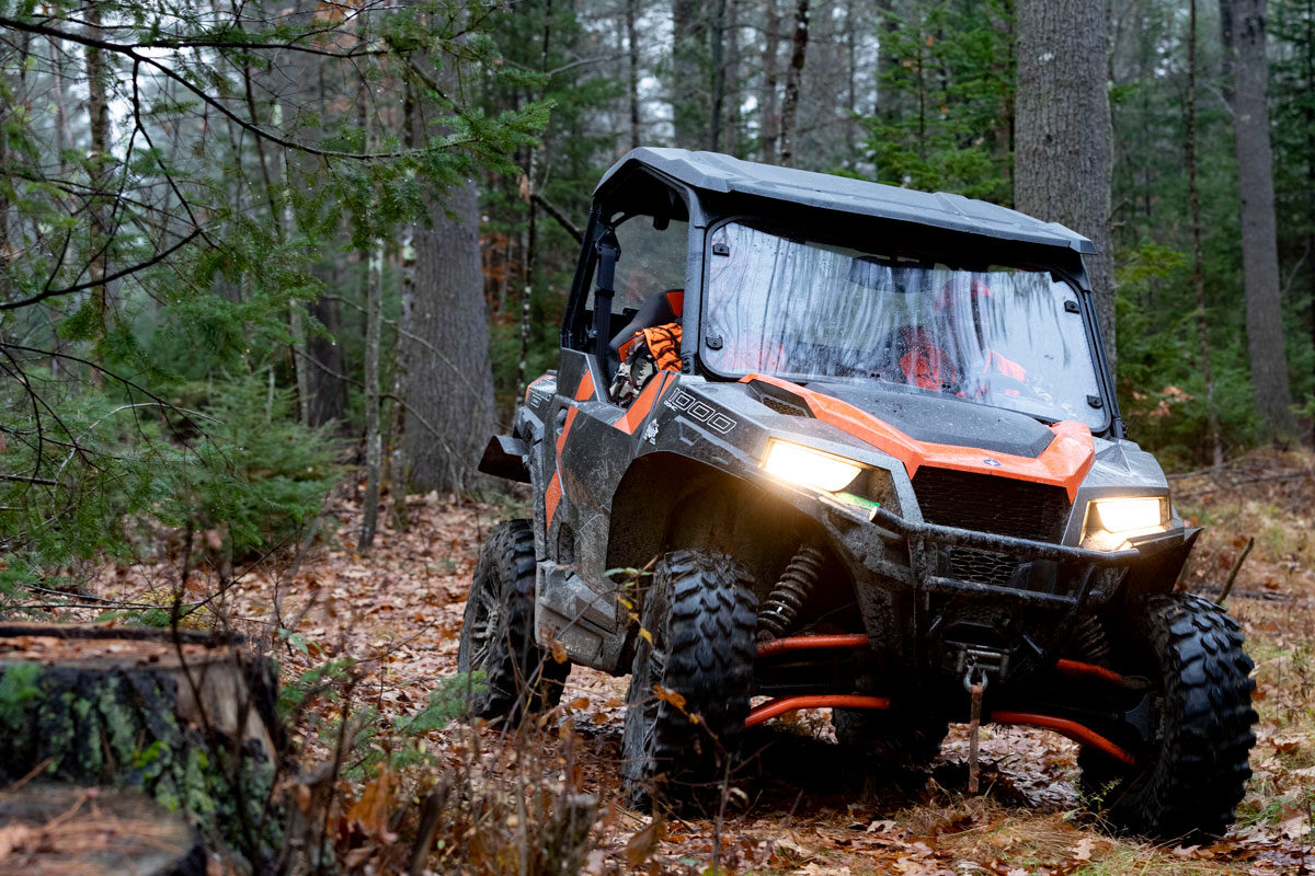 Orange and black side-by-side driving in the woods