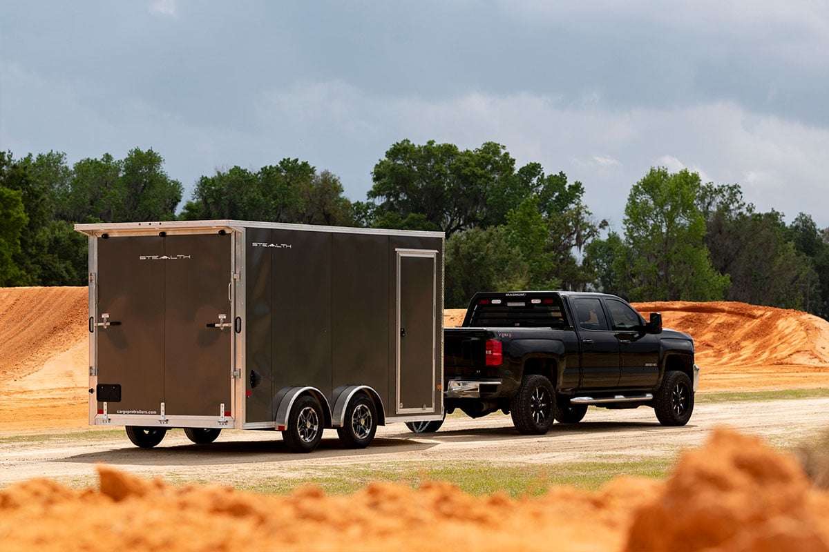 Gray enclosed aluminum cargo trailer loaded with dirt bikes on a summer adventure