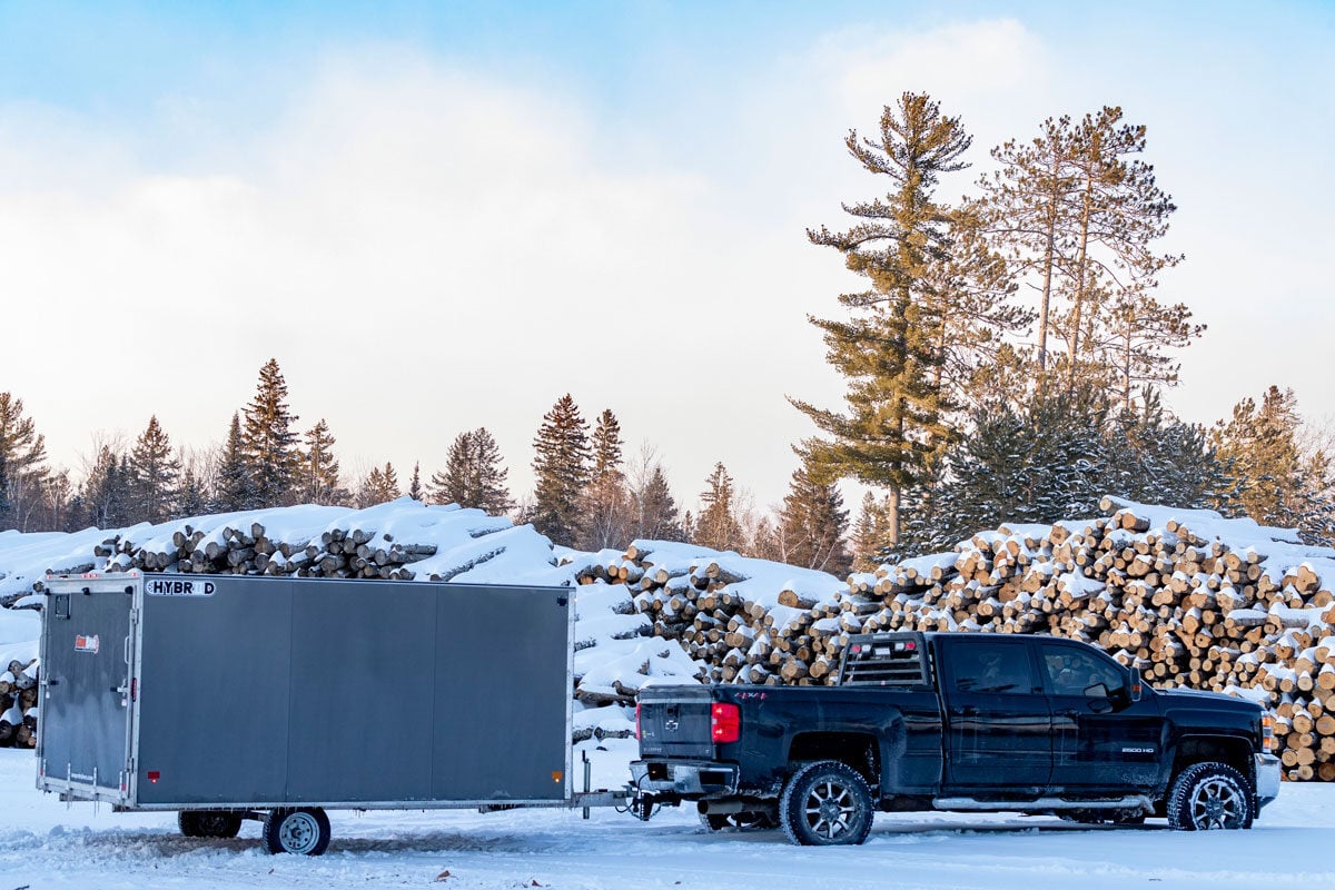 SnoPro Hybrid 2.0 and truck parked by firewood stack