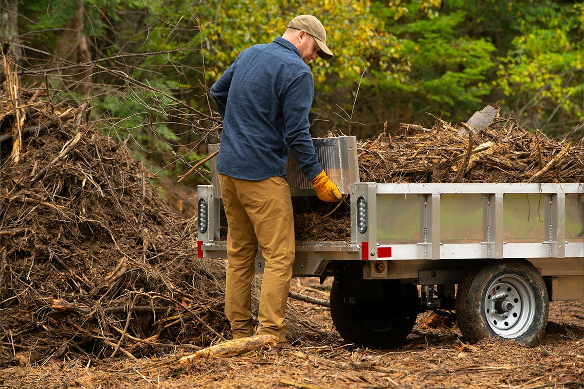 Homeowner places the rear panel/ramp on a loaded aluminum residential dump trailer