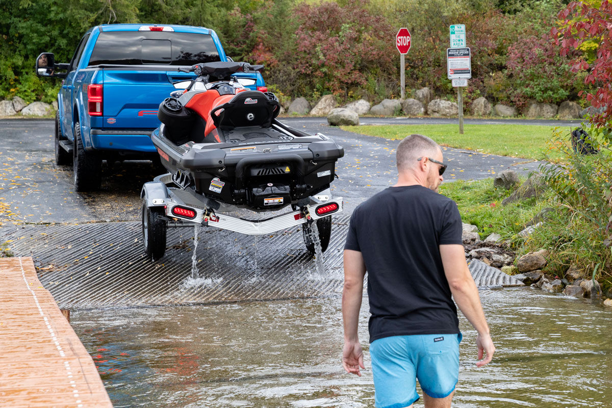 WAVE Series aluminum single-place trailer towed up a boat ramp with one PWC loaded